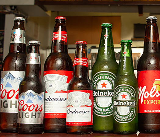 Des bouteilles de bière de différentes marques sont alignées sur le bar.