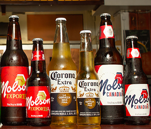 Multiple brands of beer bottles lined up on the bar.